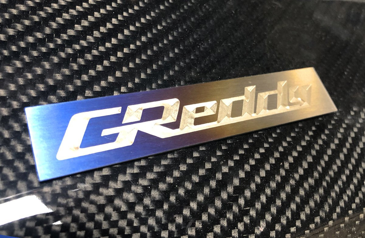 GReddy Optional Titanium GReddy Emblem - (105x20mm)